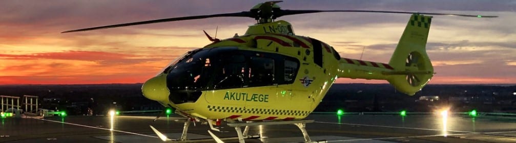 Akuttlegehelikopter fra den danske operasjonen parkert.  Solnedgang i bakgrunnen.