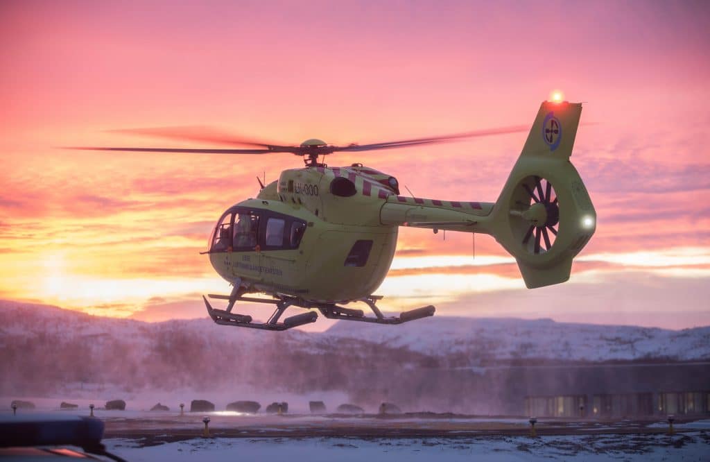 Helikopter rett før landing på landingsplass i solnedgang. 